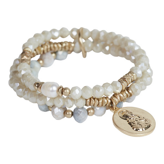 The Moshi Armband Naomi mit weißen Glasperlen und goldfarbenem Buddha Anhänger, elastisches Perlenarmband Set