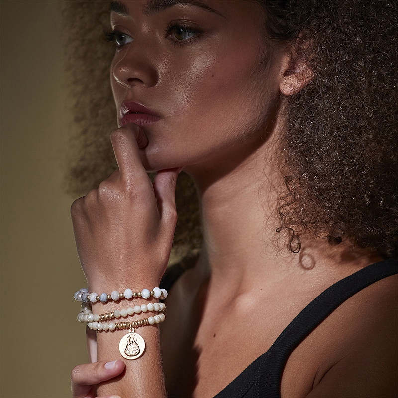 The Moshi Armband Naomi mit weißen Glasperlen und goldfarbenem Buddha Anhänger, elastisches Perlenarmband Set am Handgelenk getragen