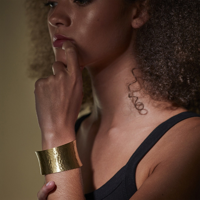 The Moshi goldfarbener Armreif aus Messing – breite offene Armspange am Handgelenk getragen